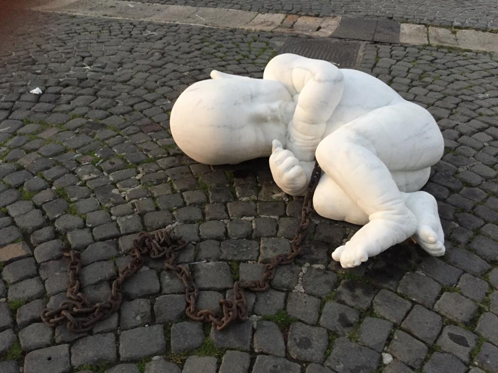 Un bambinello di marmo di 700 chili, con tanto di catena e titolo provocatorio “Look down” a Piazza Plebiscito. A chi piace, a chi no!